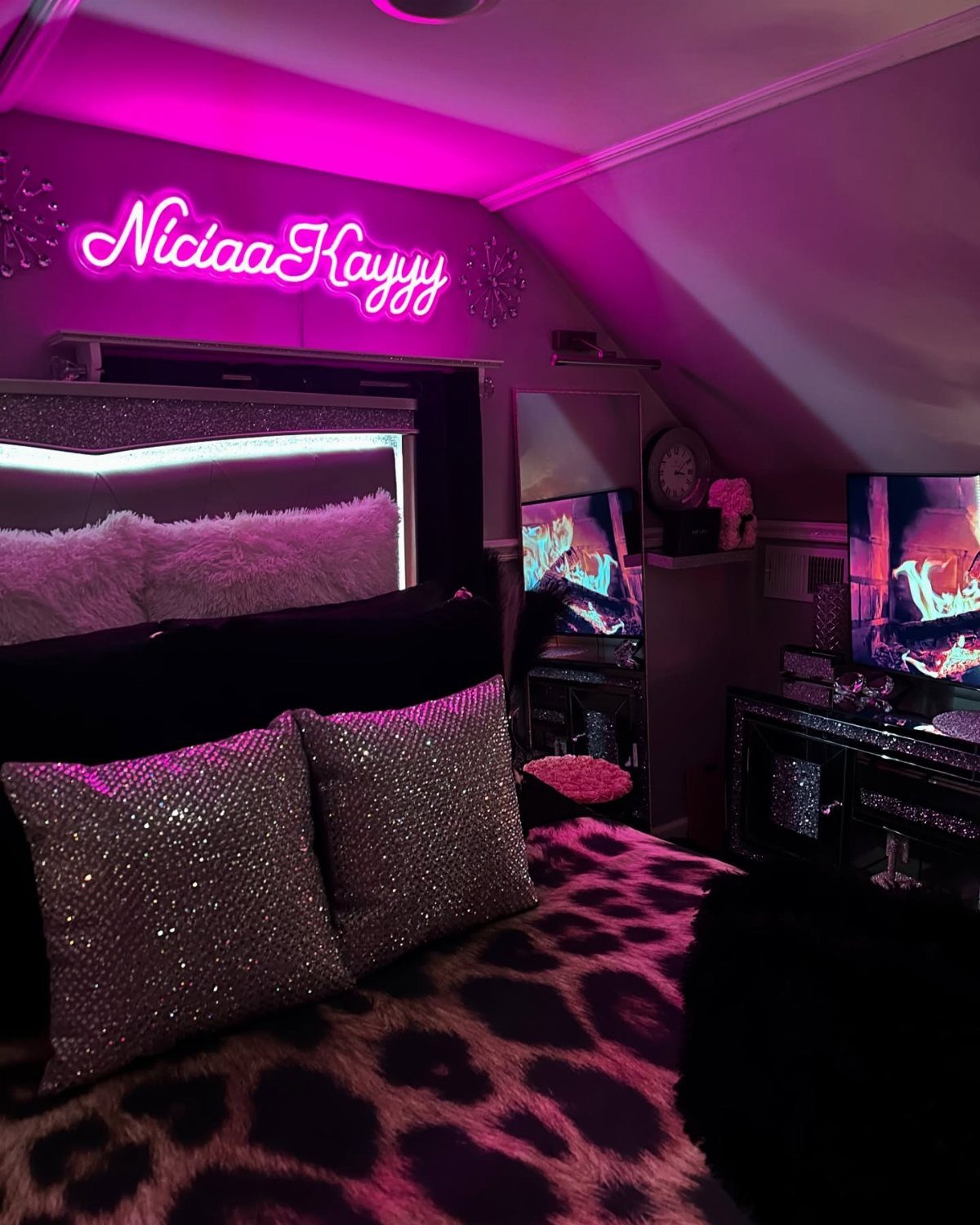 Leopard print blanket and sparkly pillows in a bedroom with pink neon lighting.