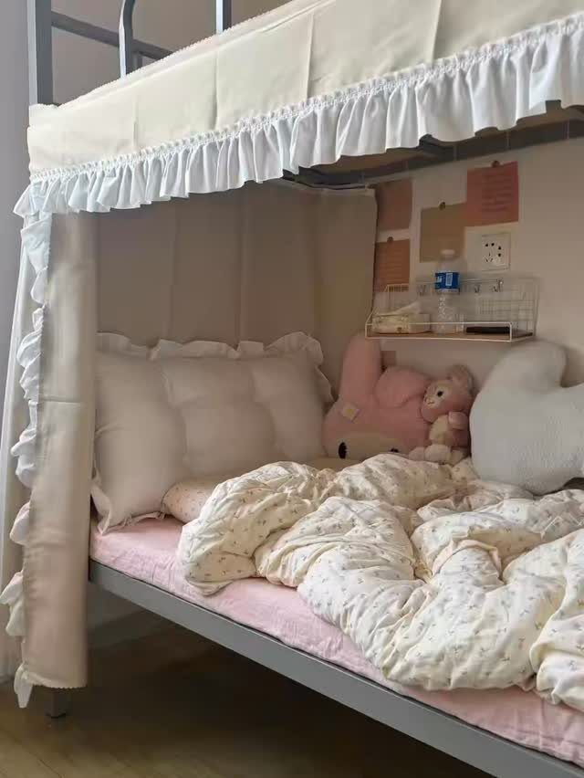 Bottom bunk bed with white ruffled canopy, pink bedding, and plush toys.