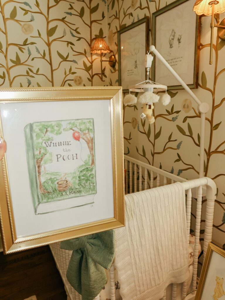 Winnie the Pooh book illustration in gold frame against a nature-themed nursery background
