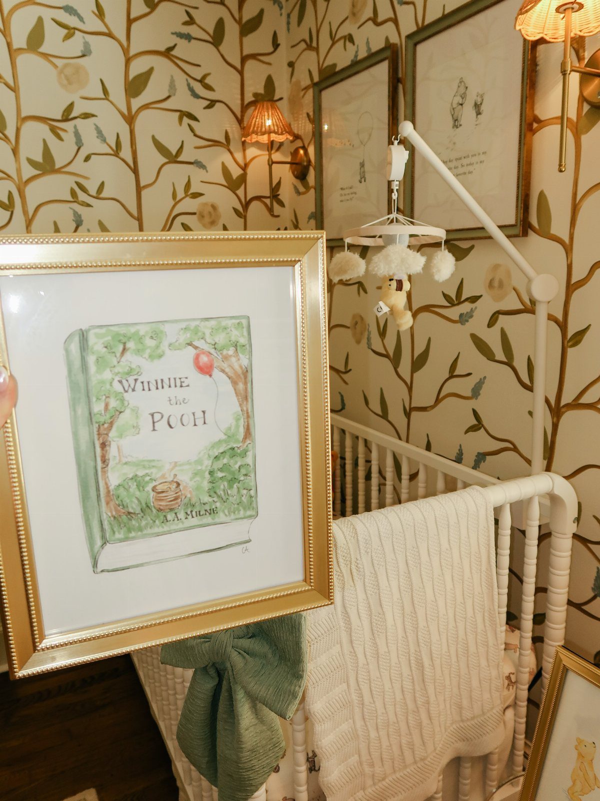 Winnie the Pooh book illustration in gold frame against a nature-themed nursery background