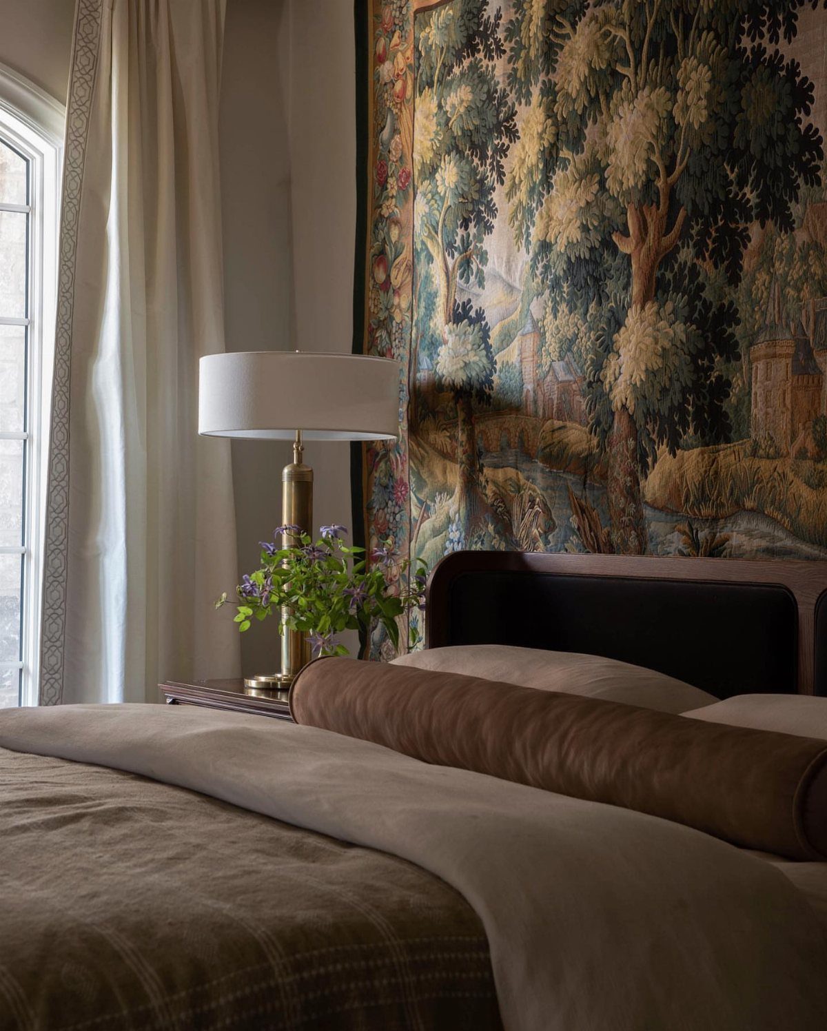 Landscape tapestry hanging on a wall behind a bed as a headboard