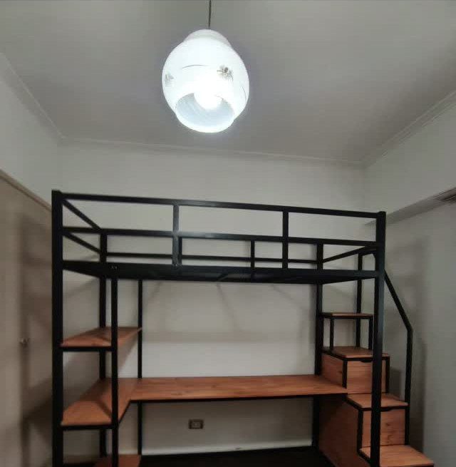 Black metal loft bed with wooden desk and shelving units underneath.
