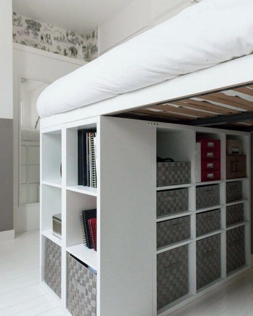 White loft bed with a white shelving unit and storage baskets underneath.