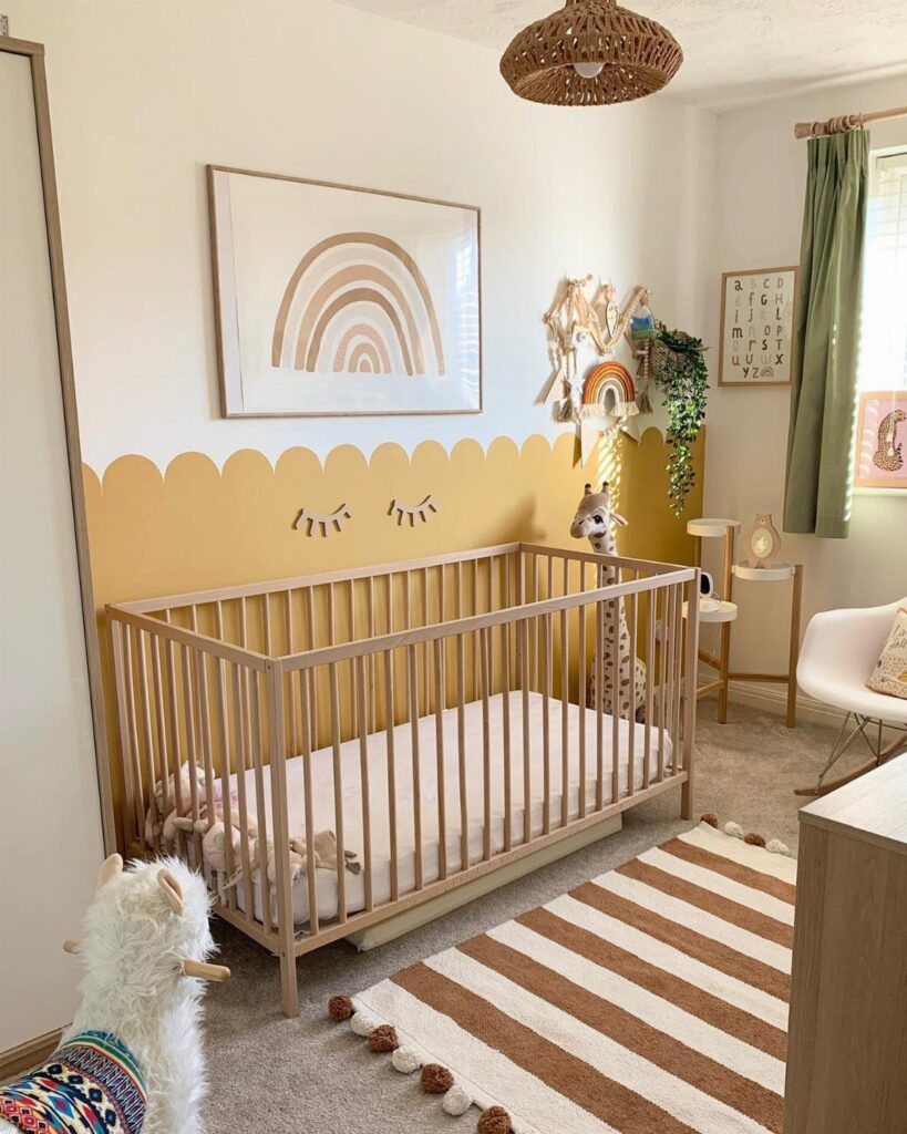 Boho nursery with a light wood crib, rainbow art, and striped pom-pom rug.