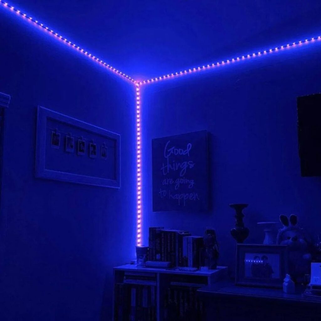 Blue LED strip lights lining the ceiling and wall corner of a bedroom