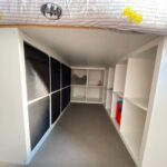 White loft bed with integrated shelving and black storage bins underneath.