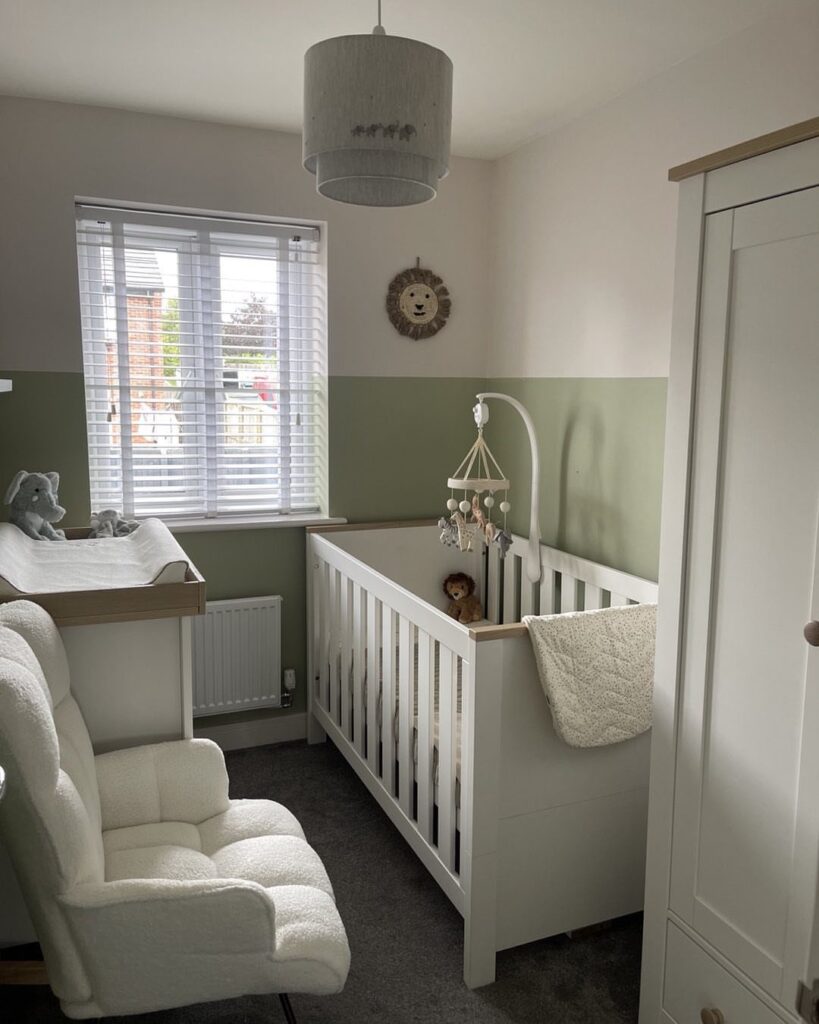 Small baby nursery with white crib, glider chair, and sage green walls.