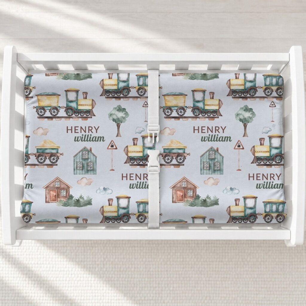White changing table with a blue train patterned changing pad for a baby.