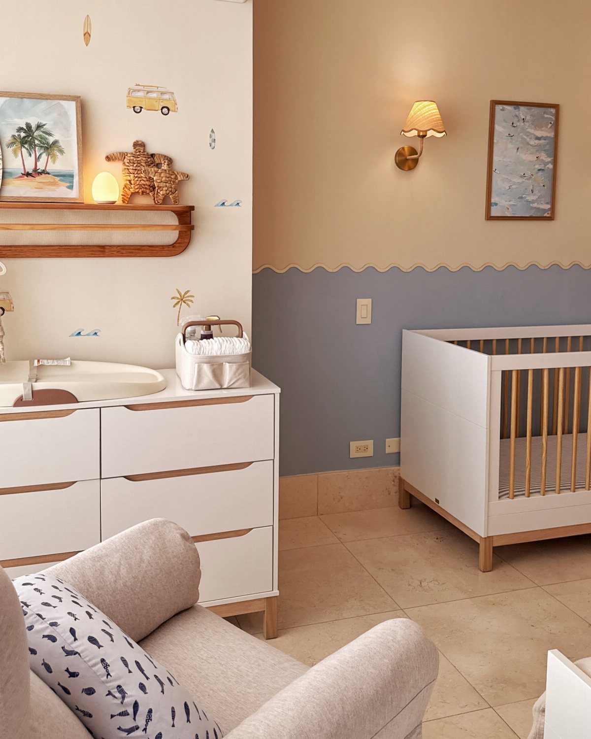 Nursery room with blue and beige walls, white crib, and ocean themed decor.