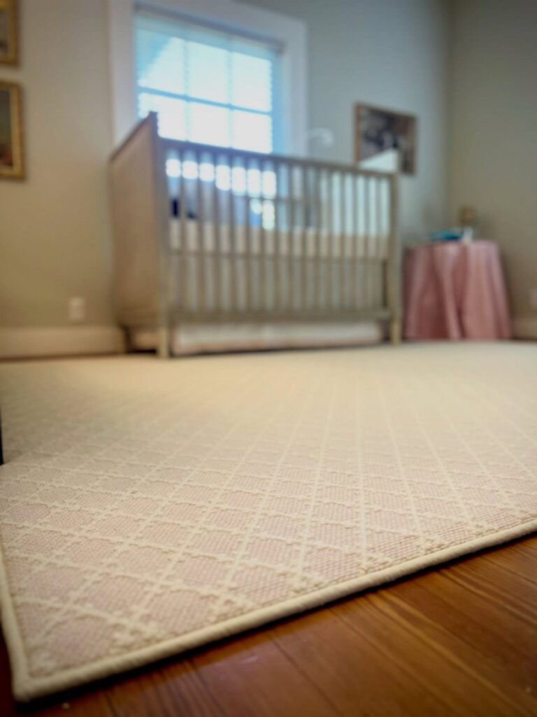 Light patterned rug on wooden floor in a nursery with a white crib.