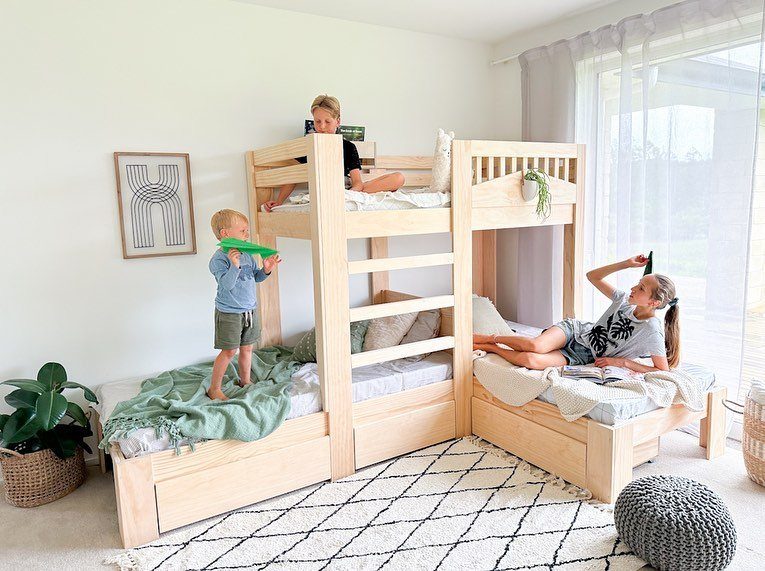 L-shaped light wood bunk beds in a bright room with three children playing.