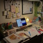 Study desk with anatomy textbook, tablet, colorful pens, and a desk lamp.
