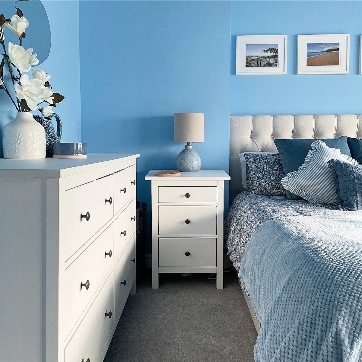 Light blue bedroom walls with white furniture and blue bedding in a small room.