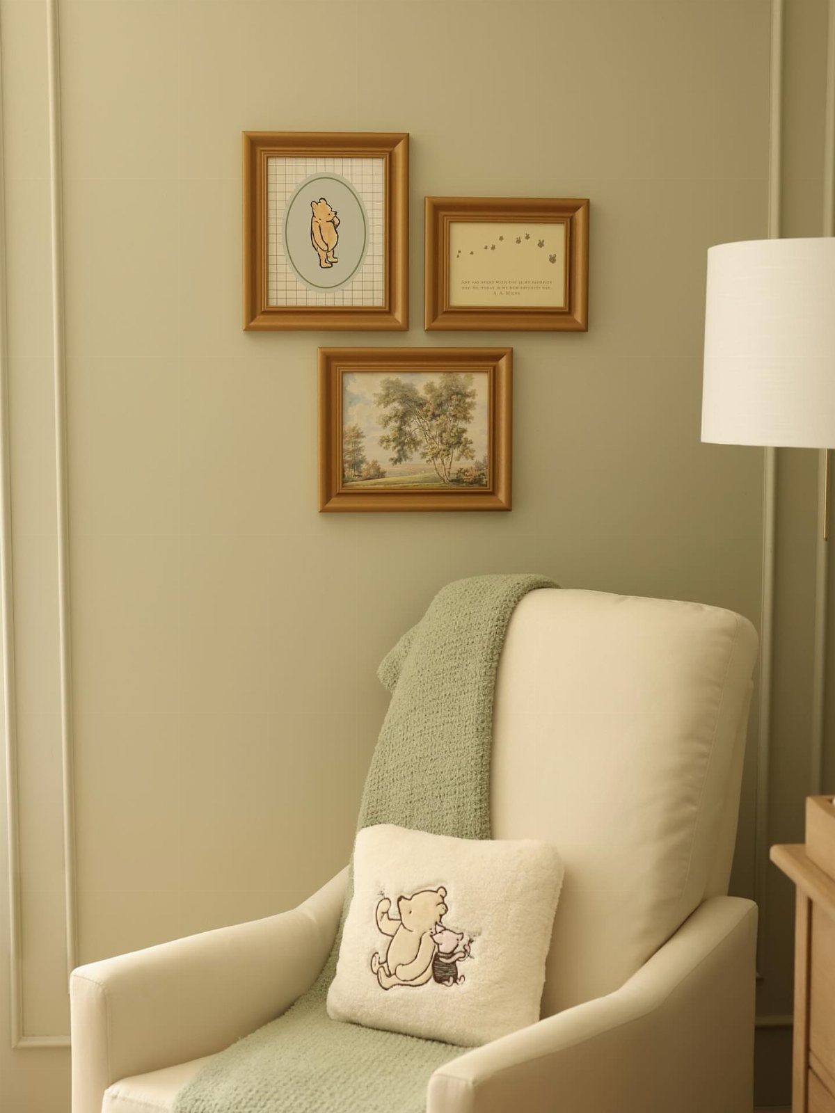 Cream armchair with Winnie the Pooh pillow and framed art on green walls